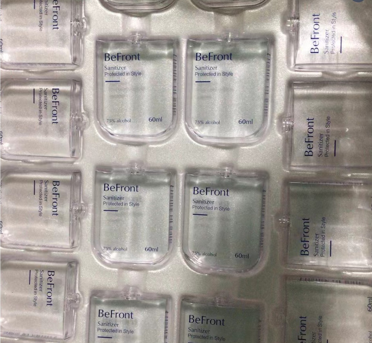 A 50ml spray bottle shown in three scenarios: airport security tray, being refilled from a large bottle, and placed inside a subscription box