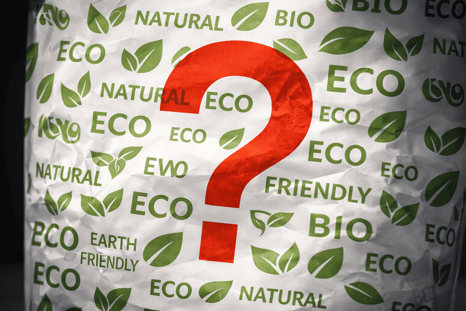 A product label covered with green symbols and vague eco claims, highlighted with a warning question mark