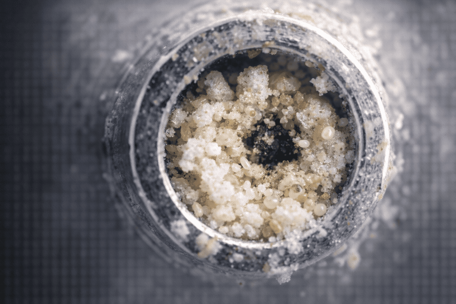 A magnified view of a spray nozzle opening blocked by dried residue and tiny particles from the formula