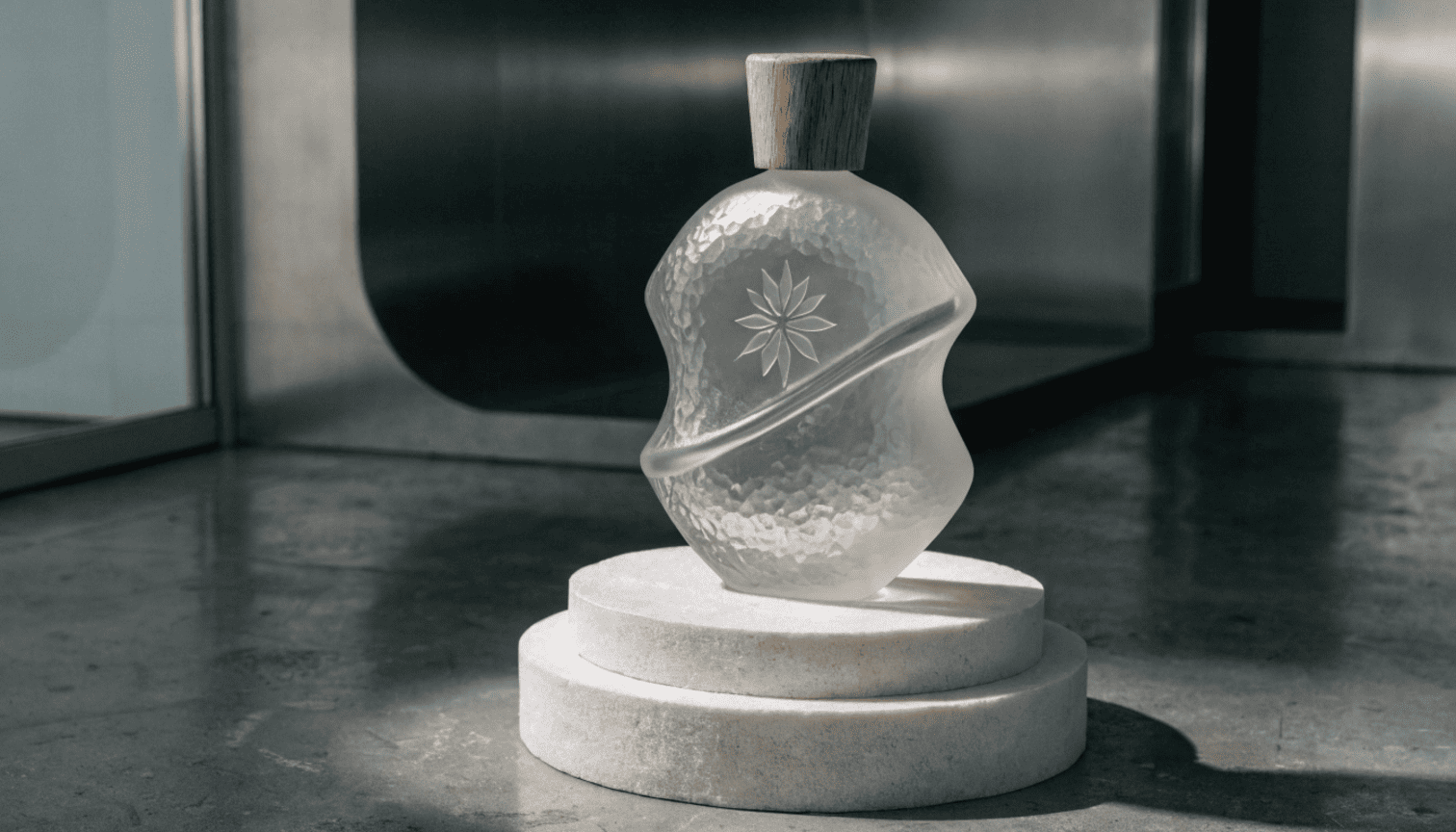 A uniquely shaped cosmetic bottle with a debossed logo displayed under spotlight to emphasize exclusivity